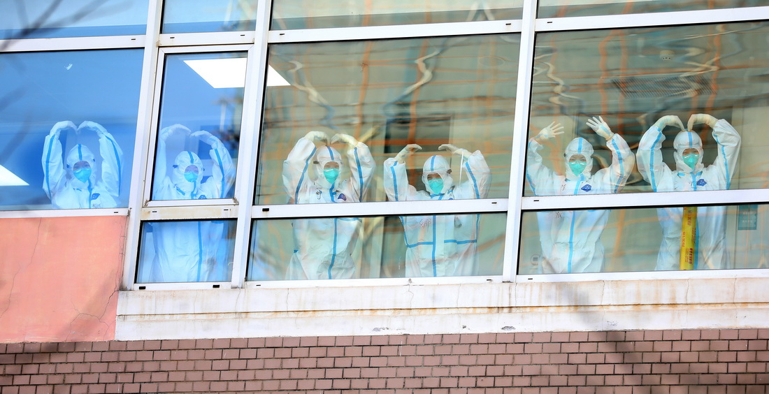 11月19日，幾名遼寧省新冠肺炎集中救治大連中心醫護人員在隔離病房的走廊裡向窗外做出愛心手勢。新華社記者 姚劍鋒 攝