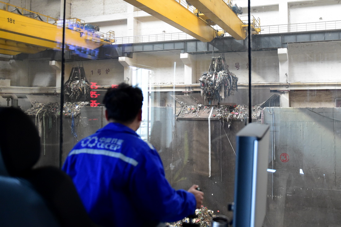 11月23日，在一家环保能源公司，工作人员操作垃圾吊抓斗将垃圾投入燃烧炉。新华社记者 黄博涵 摄