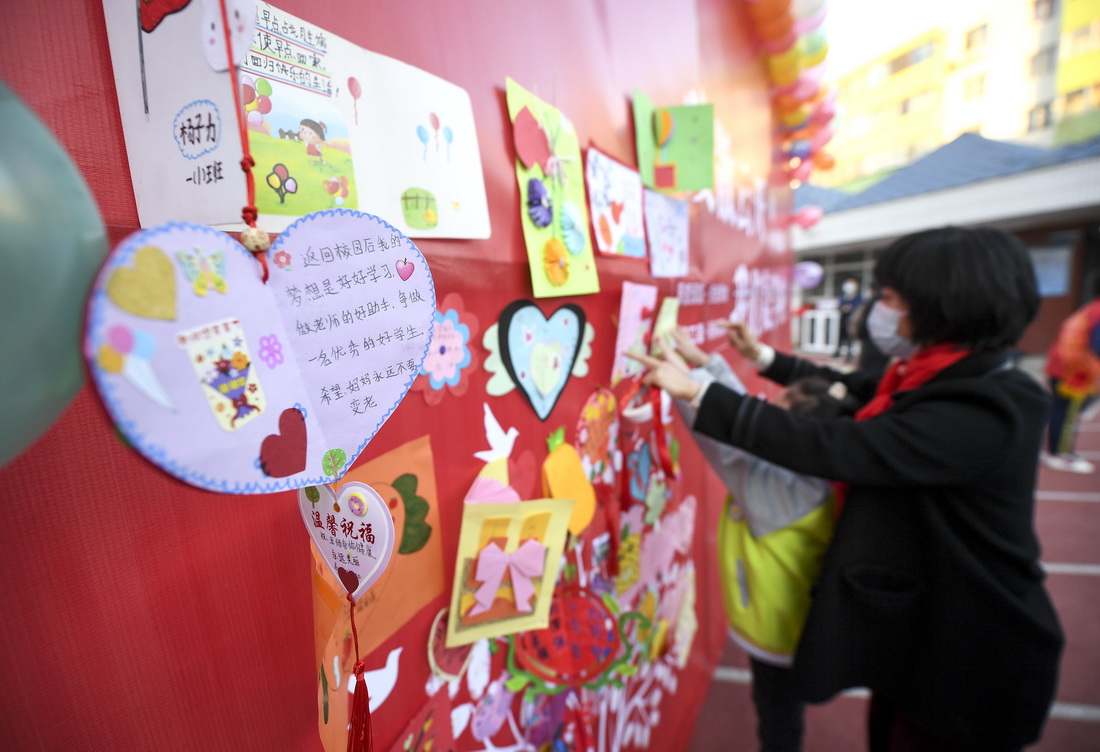 11月25日，宁夏银川市兴庆区第四小学老师帮助学生将复学心愿卡贴在入校心愿墙上。