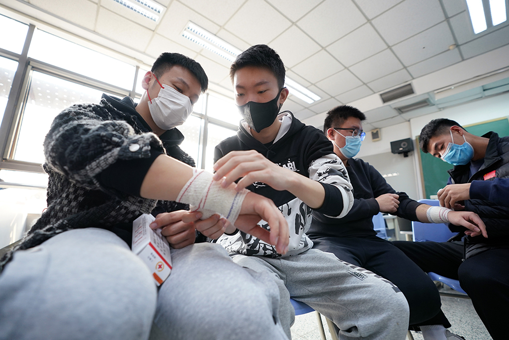 楊曦（左二）在學校參加冬奧志願者急救技能培訓時與同學一起練習包扎（11月27日攝）。新華社記者 鞠煥宗 攝
