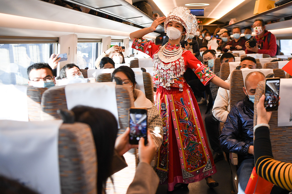 12月6日，工作人员身着苗族服饰在首趟正式运营的张吉怀高铁列车上为乘客表演。