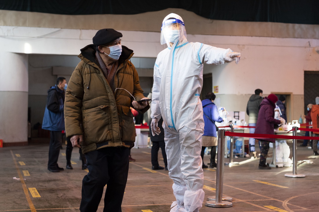 12月11日，在哈爾濱市香坊區哈爾濱理工大學核酸檢測點，關超（前右）引導市民進行核酸採樣。新華社記者 謝劍飛 攝