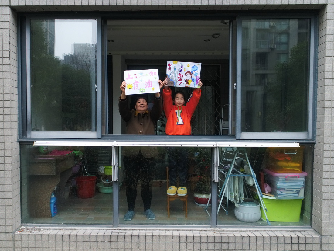 12月16日，喜愛畫畫的小學生馮若烯和奶奶任女士在家中一起舉著畫作為戰“疫”鼓勁（無人機照片）。
