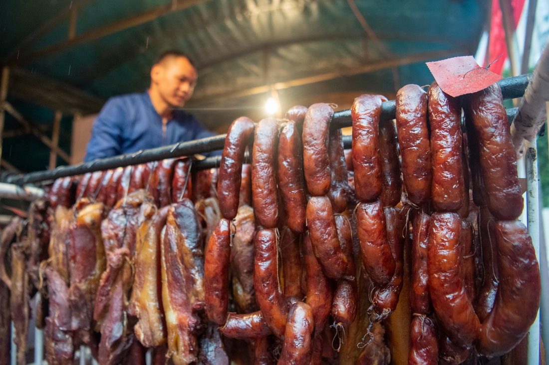 12月18日，在位于重庆市渝北区龙溪街道的“无烟熏制腊肉便民服务点”，工作人员在整理熏制好的腊味年货。