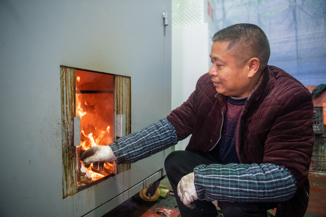 12月18日，在位於重慶市渝北區王家街道的“無煙熏制臘肉便民服務點”，工作人員在操作“熏肉神器”。