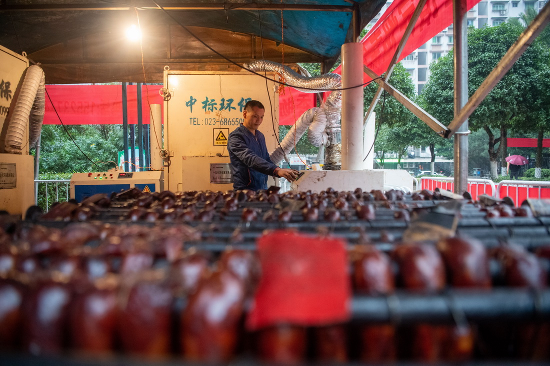 12月18日，在位于重庆市渝北区龙溪街道的“无烟熏制腊肉便民服务点”，工作人员在操作“熏肉神器”的净化系统以降低空气污染。