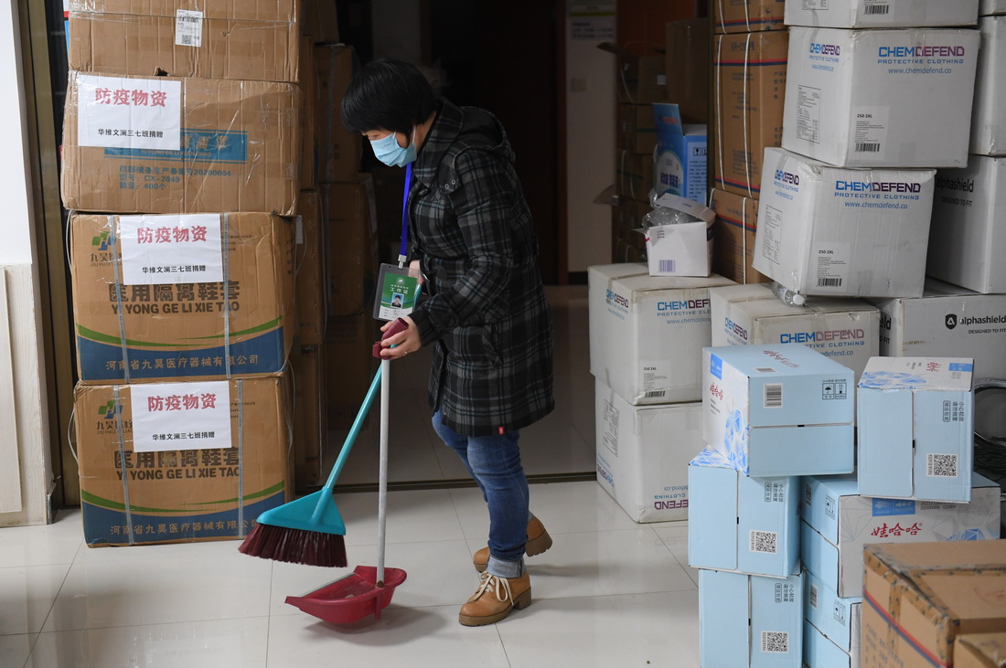 晚上八點多，宋惠清打掃社區居委會內的衛生，狹小的辦公空間裡堆滿了政府派發和各界人士捐助的抗疫物資（12月18日攝）。