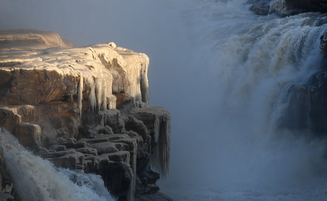 12月22日，一束陽光照射在黃河瀑布的冰瀑上。