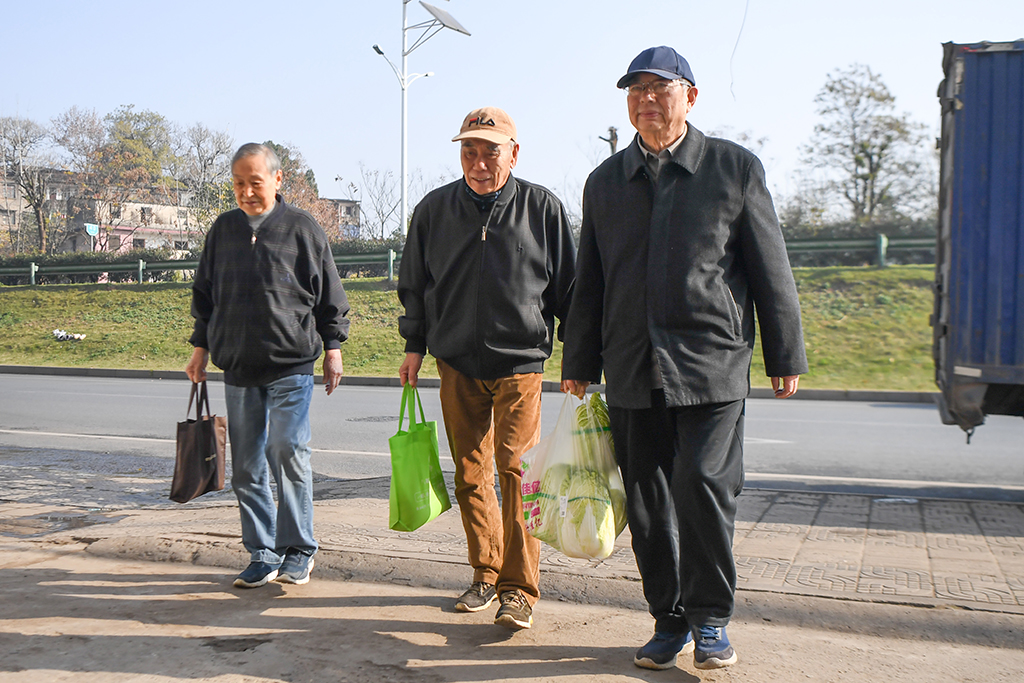 12月23日，魏镇、马利民、余国基（右起）提着备好的面、菜来到宝南饭店。