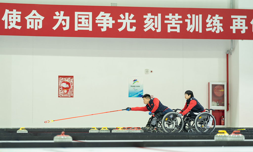 12月23日，在北京顺义中国残疾人体育运动管理中心的国家残疾人冰上运动比赛训练馆，中国轮椅冰壶队队员张明亮（左）、张�釉谘盗贰Ｐ禄�社记者 才扬 摄