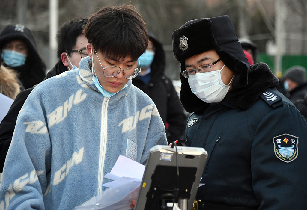 12月25日，在北京理工大学考点，工作人员（右）通过人脸识别的方式核对考生信息。