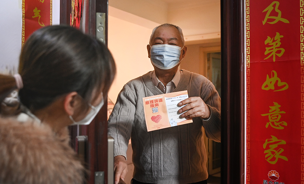 1月7日，西安市未央区一社区工作人员为居家隔离的老人（右）送上“疫情防控明白卡”。新华社记者 陶明 摄