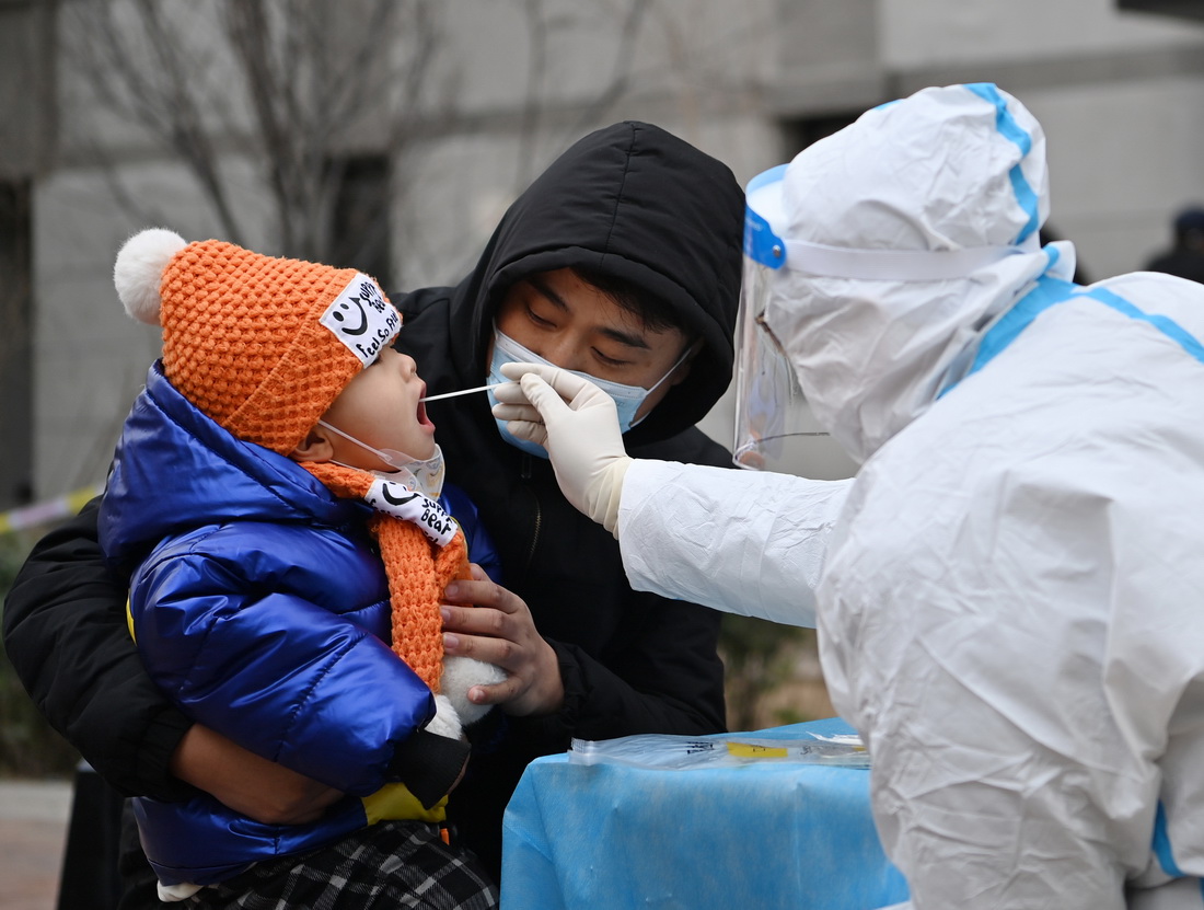 1月9日，在天津市西青區中北鎮錦曦花苑社區一處核酸檢測點，家長抱著孩子進行核酸檢測。新華社記者 李然 攝