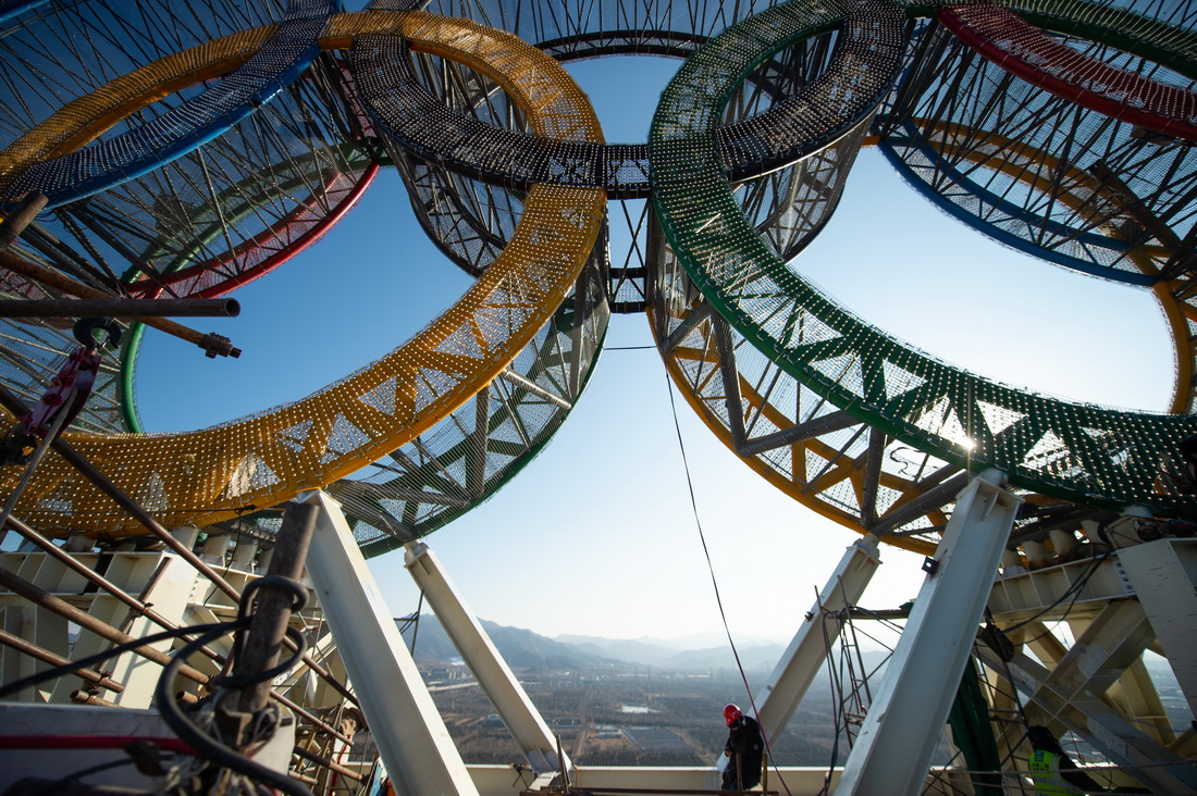 1月11日，工人們在“海陀塔”塔頂的奧運五環標志下作業。