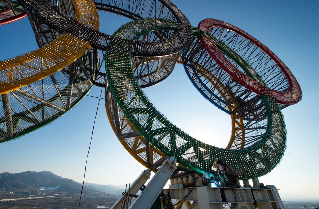 1月11日，工人們在“海陀塔”塔頂的奧運五環標志下作業。
