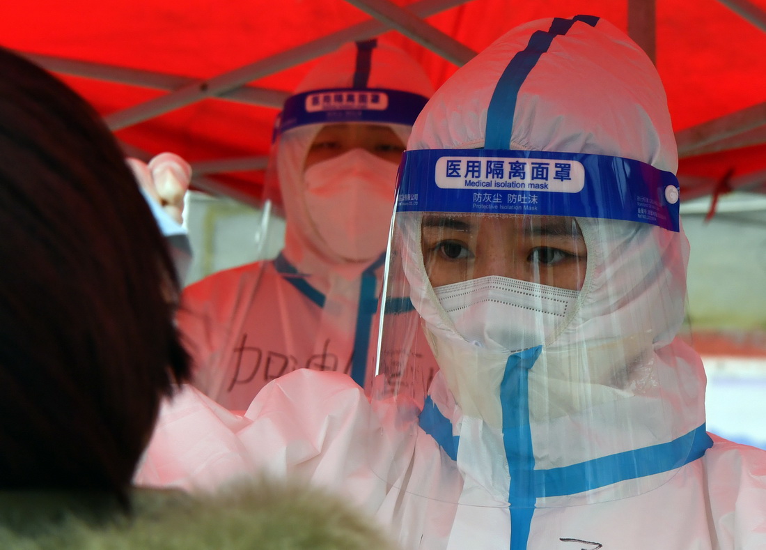1月11日，在禹州市韩城街道前屯社区，张文文（右）进行核酸采样。