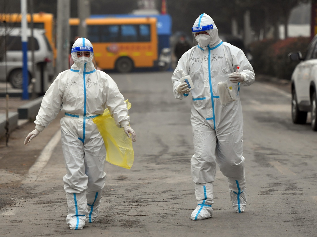 1月11日，在禹州市韩城街道前屯社区，许沛（右）与张文文在入户采集核酸的路上。
