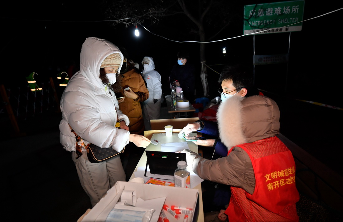1月12日，在天津市南开区广开街道某核酸检测点，志愿者帮助市民完成核酸采样登记工作。