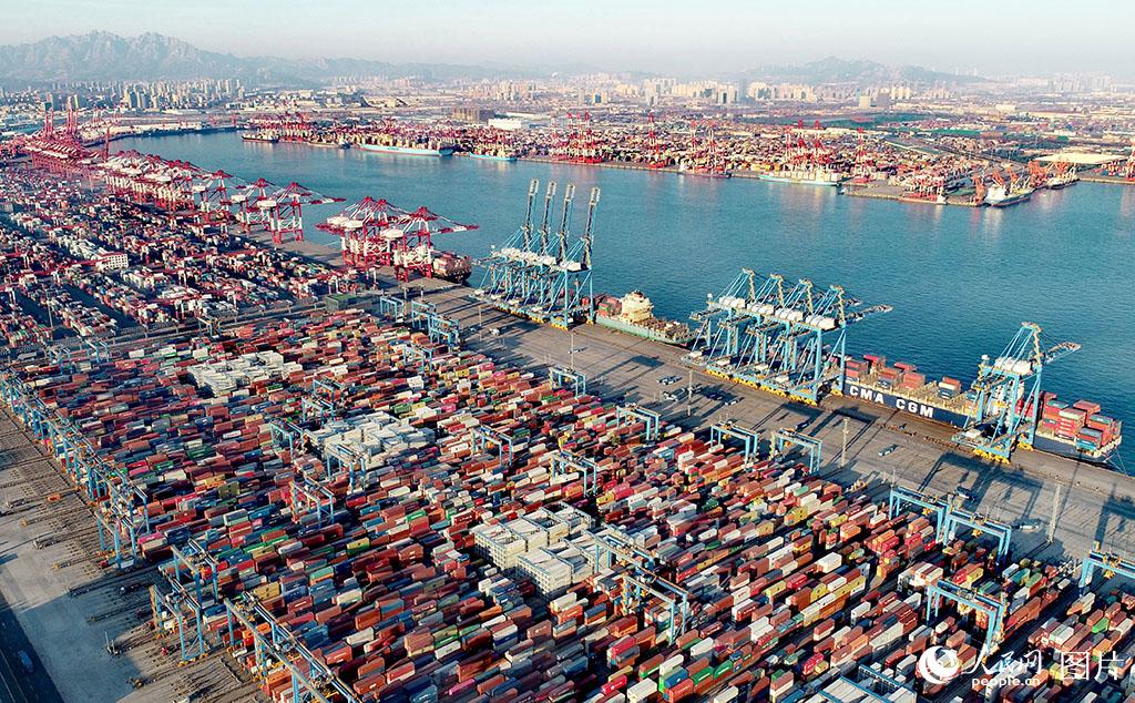 1月14日，在山東港口青島港全自動化碼頭，集裝箱堆場一派繁忙，數艘貨輪靠泊在岸邊裝卸貨物。