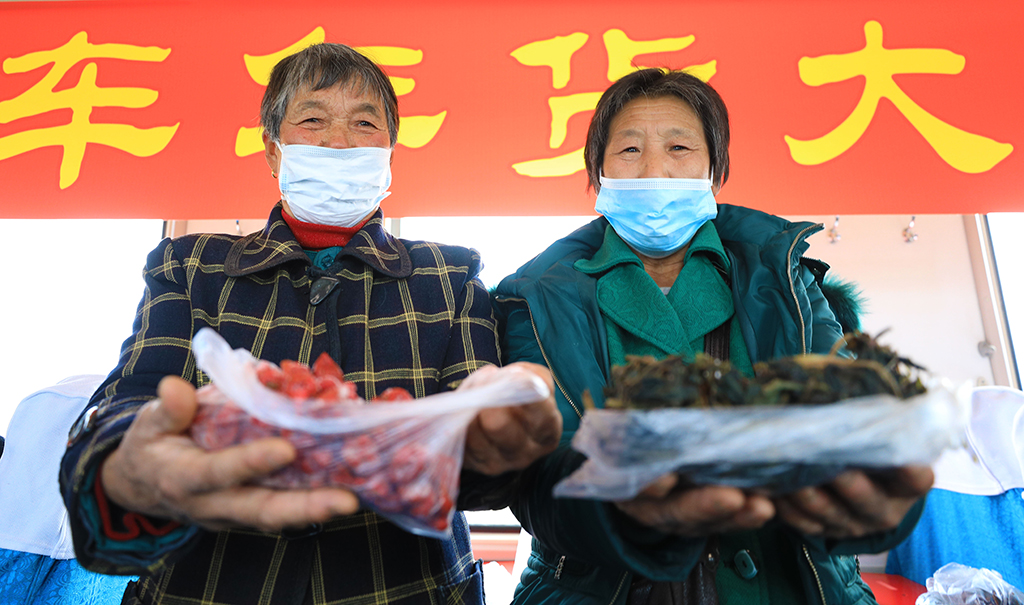 1月15日，在4318次列车上，农民们展示携带的野菜、山楂干等山货。新华社记者 杨青 摄