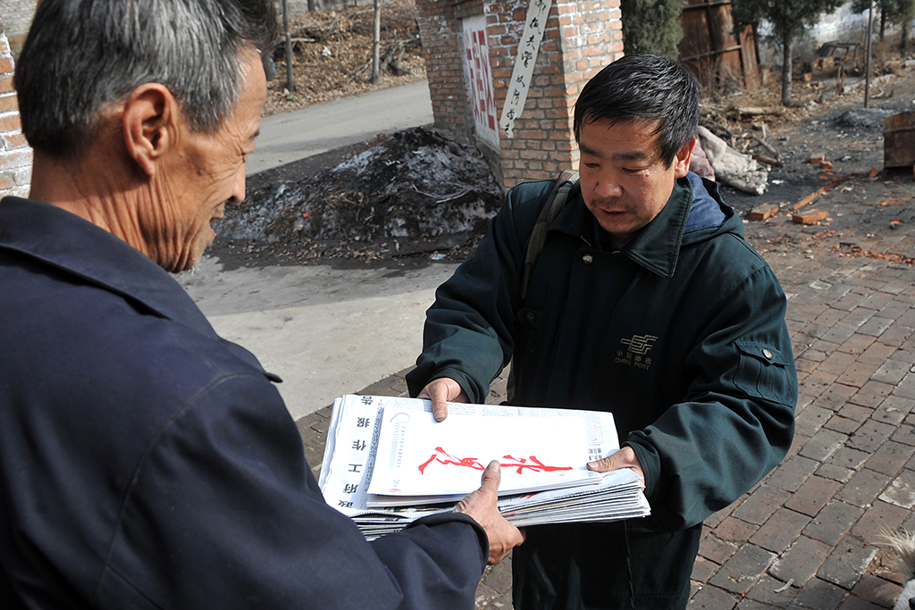 王收秋將報刊送到村民手上（2010年3月16日攝）。新華社記者 詹彥 攝