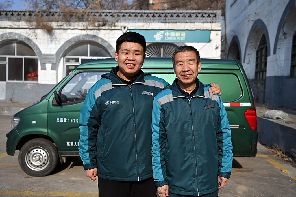王沄天（左）和父親王收秋在郵車前合影（1月5日攝）。新華社記者 詹彥 攝