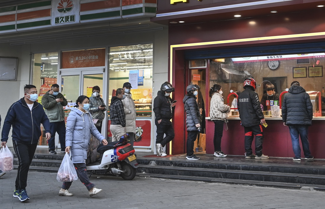 1月17日，人们在西安市碑林区一家食品店排队购买食品。