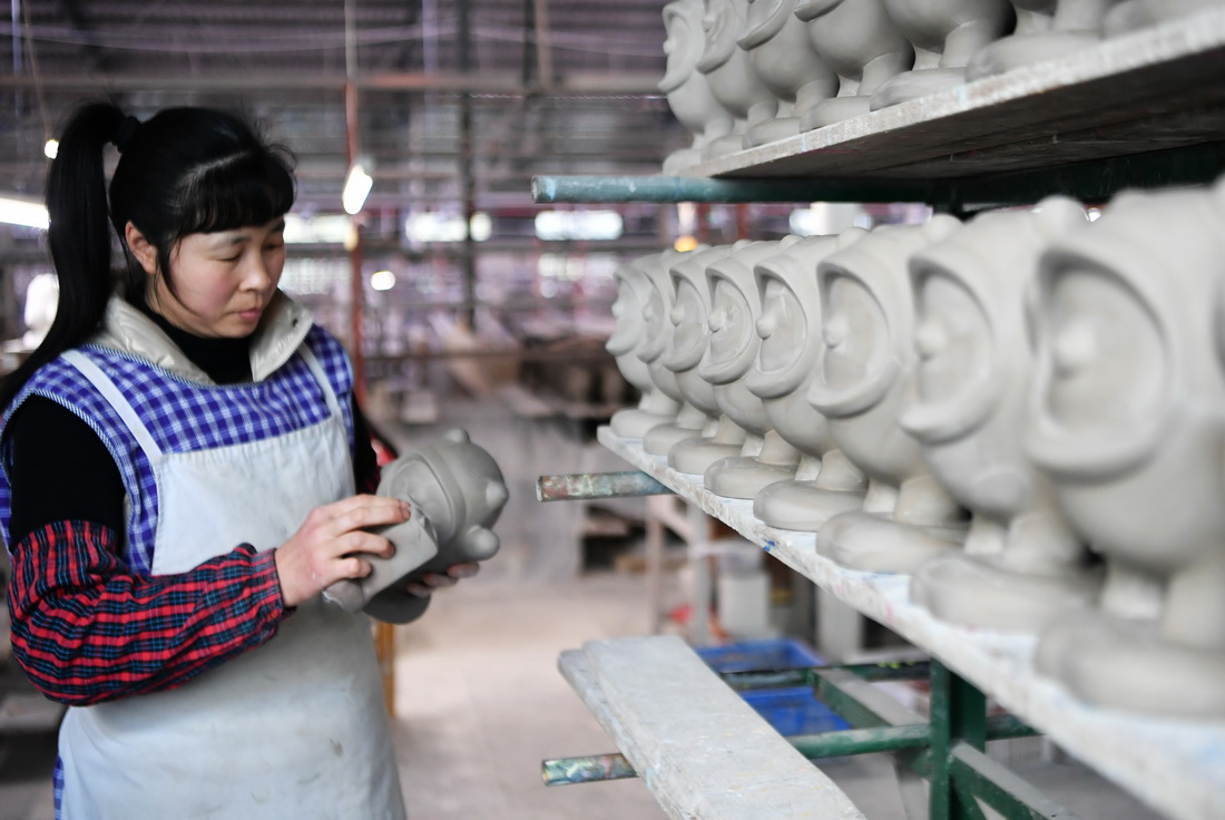 1月19日，在泉州德化縣陶瓷旅游觀光工廠的制坯成型車間，工人打磨“冰墩墩”。
