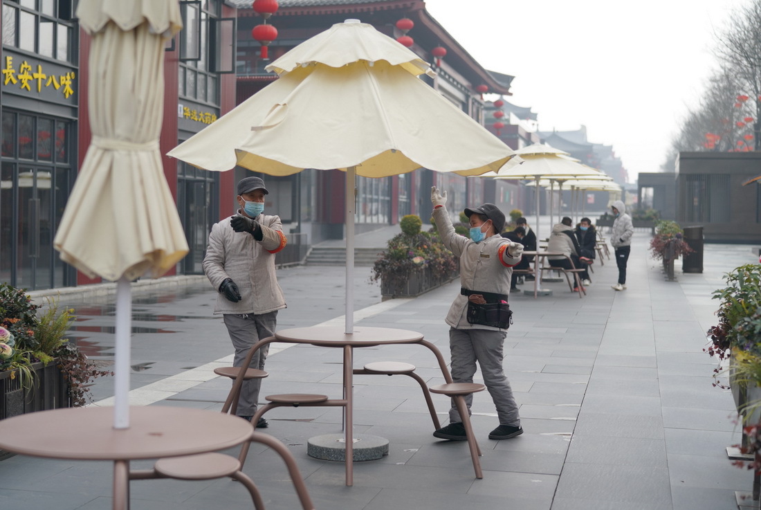 1月24日，在西安大唐不夜城，工作人員打開戶外遮陽傘。