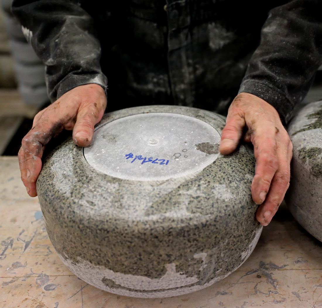 在凯斯冰壶厂，工人拿起一只标记了编号的冰壶（1月24日摄）。