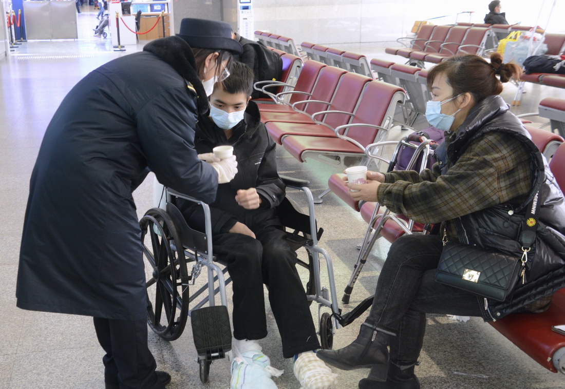 1月28日，北京西站愛心服務隊的隊員為行動不便的旅客送來熱水。
