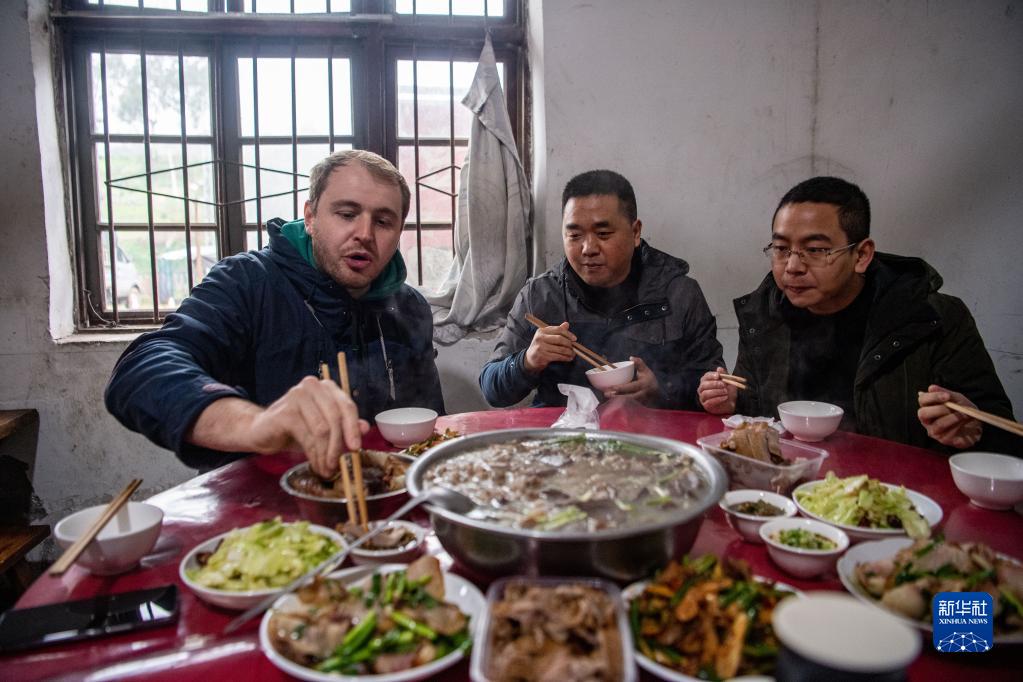 在何埂鎮柏林村，馬丁（左一）和朋友們品嘗當地年菜刨豬湯（1月27日攝）。