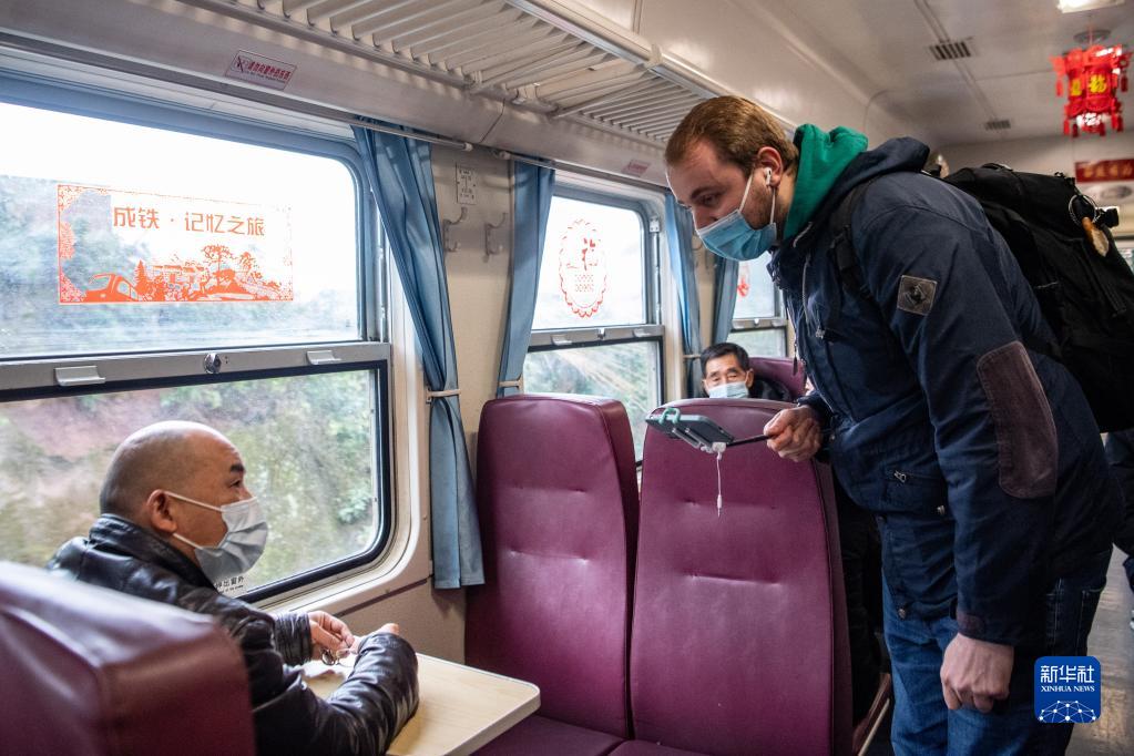 在成渝鐵路線上的“慢火車”車廂裡，馬丁（右）一邊開著抖音直播，一邊和老鄉拉家常（1月27日攝）。