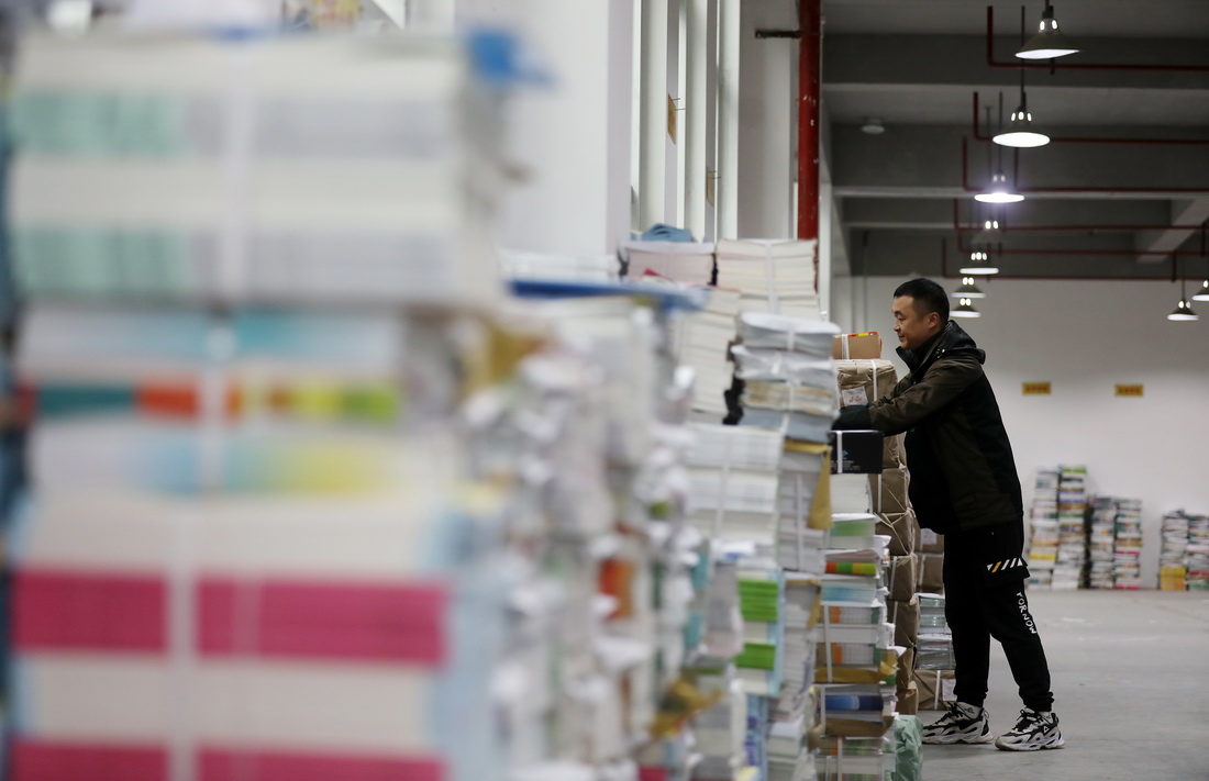 2月13日，在湖南省资兴市新华书店仓库，工作人员在清点教材。新华社发（李科摄）