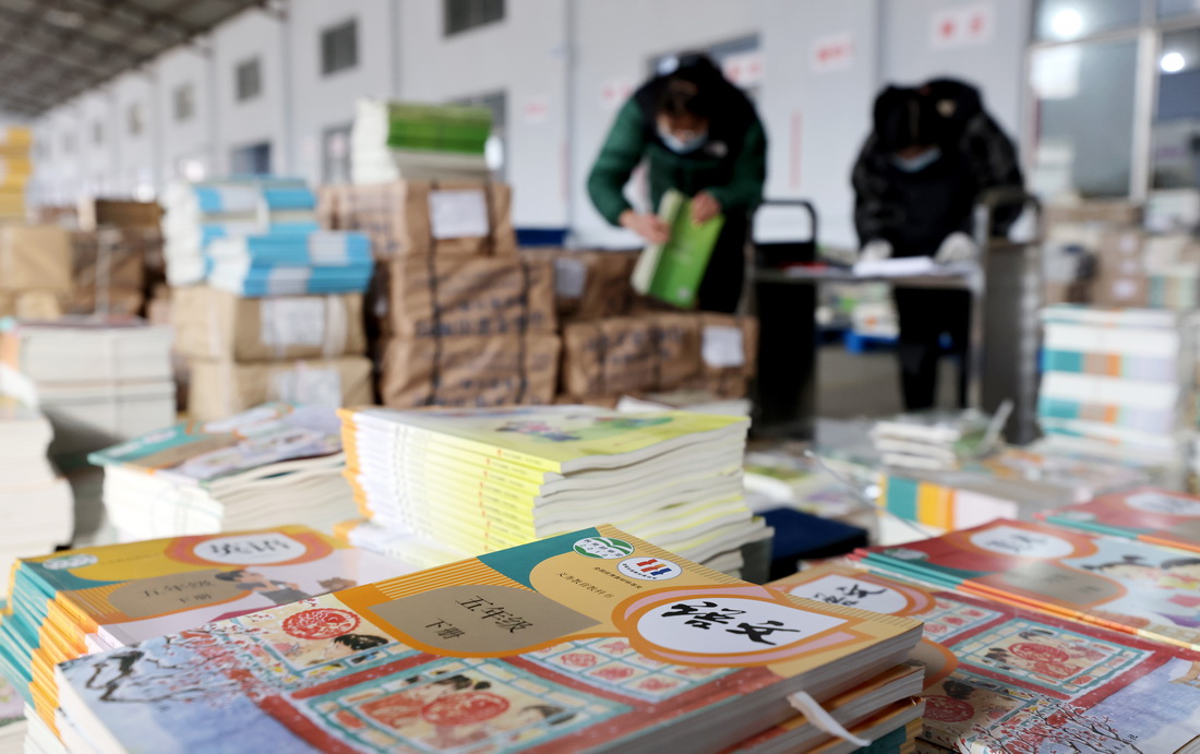 2月12日，在山东省枣庄市新华书店教材发行中心，工作人员在分拣教材。新华社发（孙中�瓷悖�