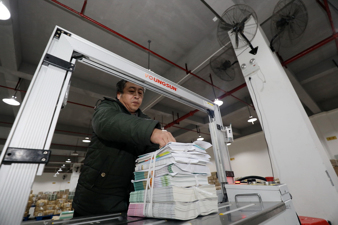 2月13日，在湖南省資興市新華書店倉庫，工作人員整理新學期教材。新華社發（李科攝）