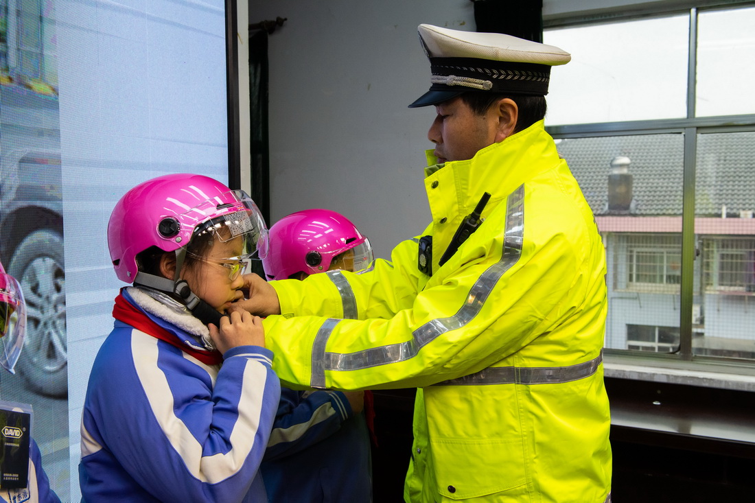 2月17日，在桃源縣實驗學校，桃源縣公安局交警大隊交警幫助學生試戴頭盔。