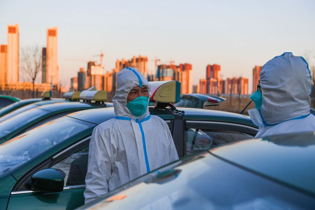 2月22日，在核酸檢測實驗室停車場，趙永紅（左）和志願者聊天。新華社記者 劉磊 攝