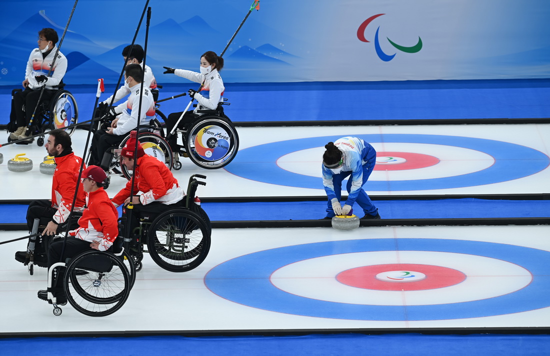 3月7日，志愿者为运动员整理冰壶。新华社记者 张博文 摄