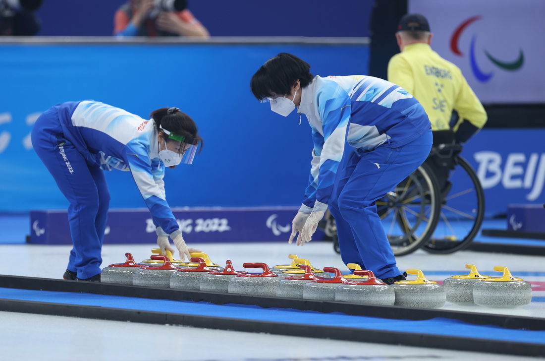 3月6日，志愿者为运动员整理冰壶。新华社记者 杜潇逸 摄