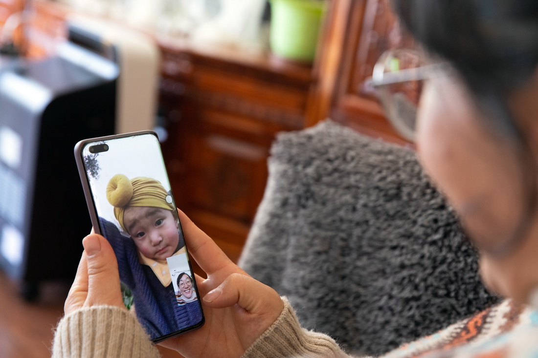 在石渠县家中，法官泽仁曲西与远在成都的儿子通过视频电话交流（1月11日摄）。目前，泽仁曲西的儿子跟着外婆在成都，丈夫在300多公里外的德格县工作，一家人分居三地，相聚时间寥寥。新华社记者 沈伯韩 摄