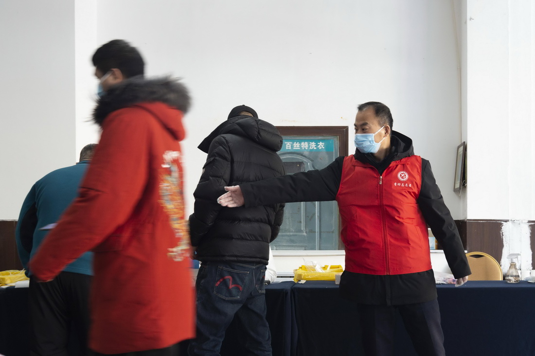 3月18日，在哈爾濱市香坊區一核酸採樣點，社區工作者（右）引導市民進行核酸採樣。