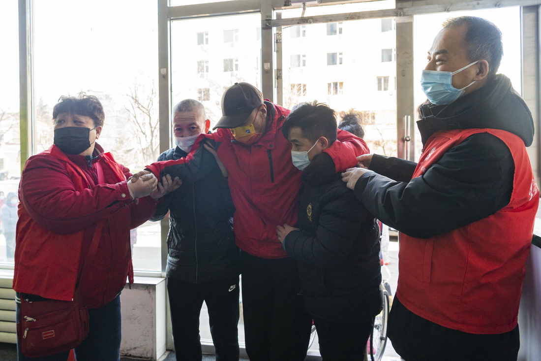 在哈尔滨市香坊区一核酸采样点，社区工作者搀扶行动不便的市民（3月18日摄）。