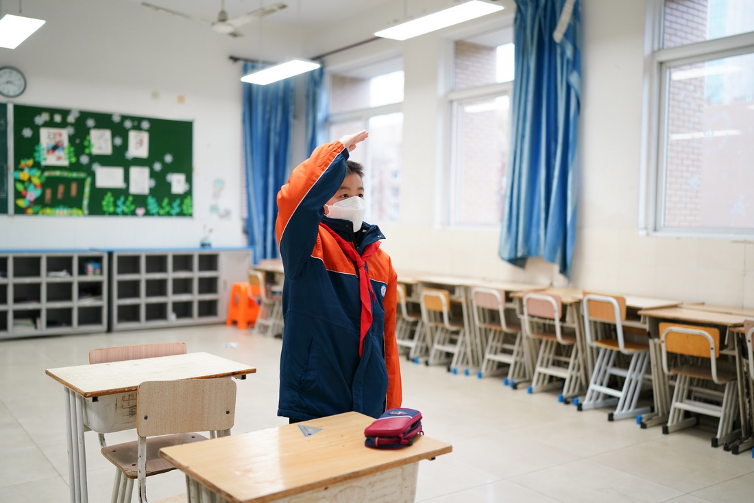 3月21日，在“空中课堂”的升旗仪式上，蒲芸帆在教室内敬礼。