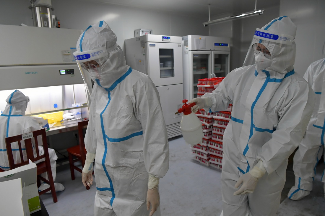 在南昌大學二附院醫學檢驗中心核酸檢測實驗室，核酸檢測員在互相消毒（3月23日攝）。