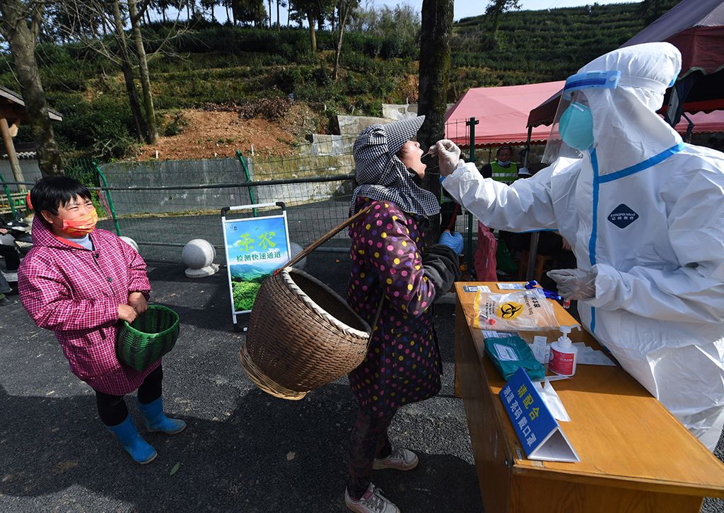 3月24日，防疫人員在杭州市富陽區銀湖街道坑西村茶山邊設立的核酸檢測“茶農檢測快速通道”為採茶工進行核酸採樣。新華社記者 徐昱 攝