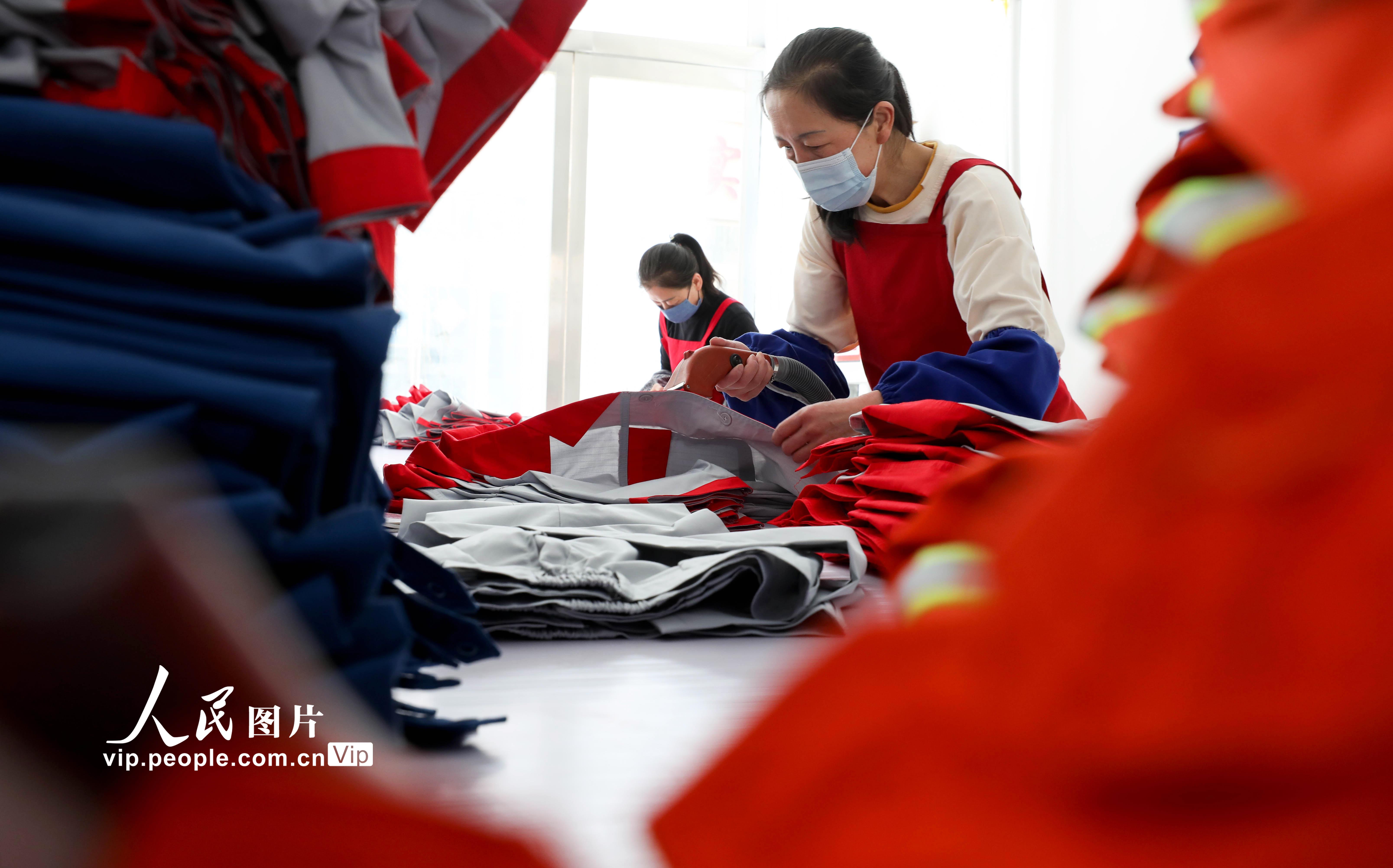 2022年3月24日，甘肅省張掖市山丹縣海蘭達服飾鄉村就業工廠內，女工們正在整理、熨燙加工好的工作服。