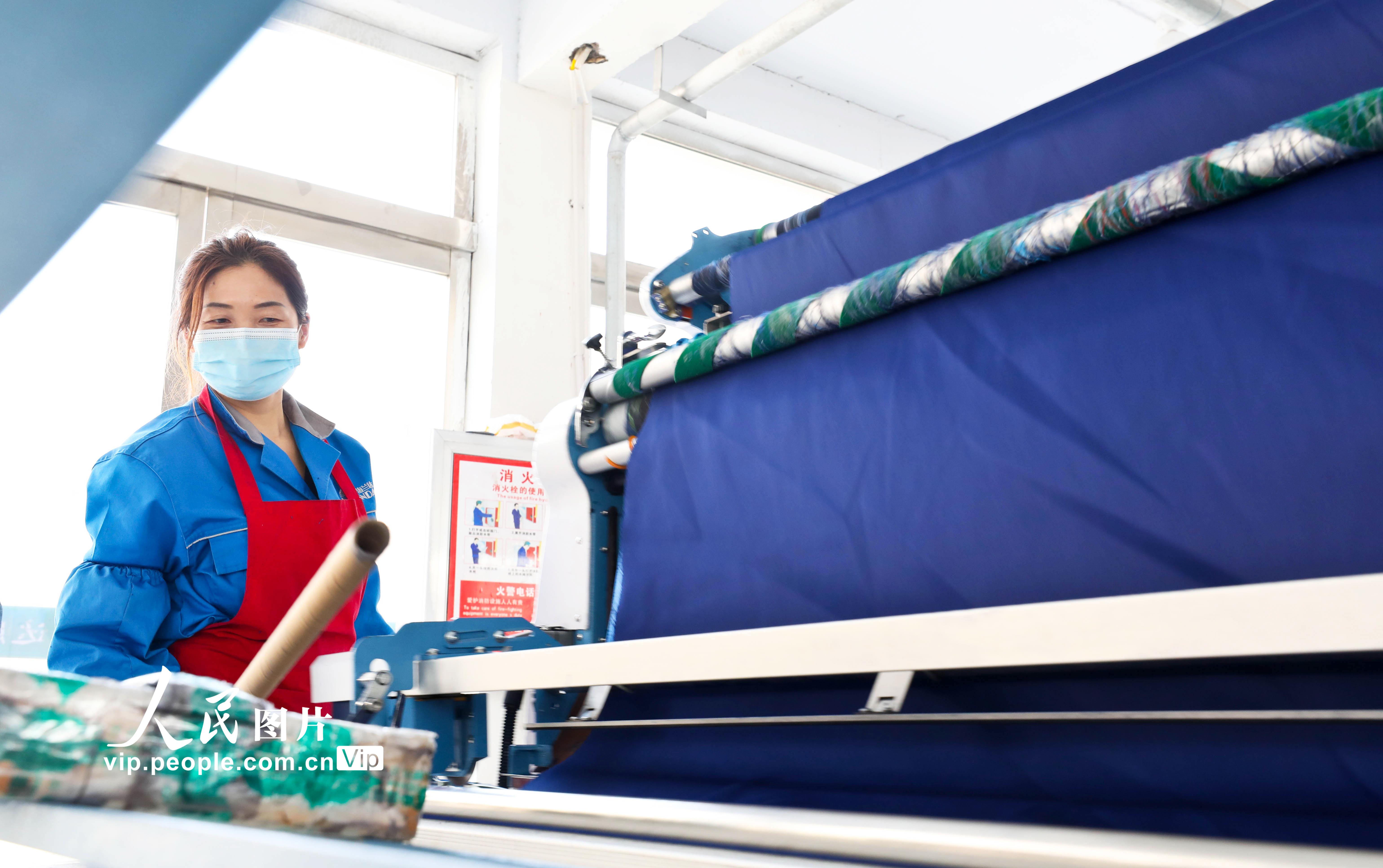2022年3月24日，甘肅省張掖市山丹縣海蘭達服飾鄉村就業工廠內，女工正在剪裁布料。