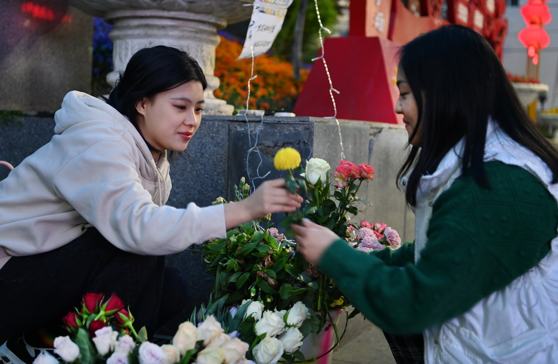 3月27日，鎮坪縣城關鎮的史棻棻（左）在夜市銷售鮮花。新華社記者 陶明 攝