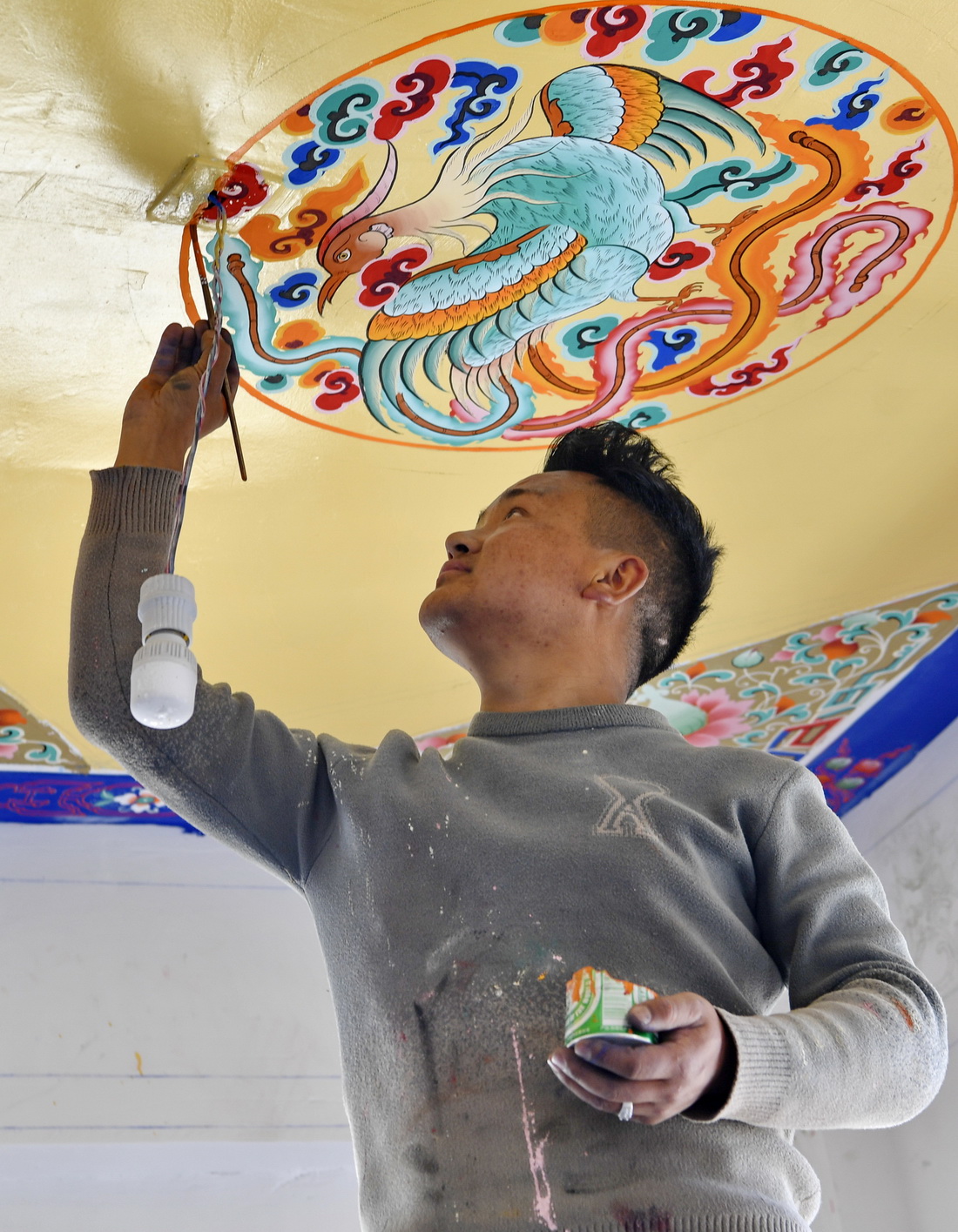 來自日喀則的民間藝人在湘河水庫移民新村一處民居繪制屋頂（3月27日攝）。